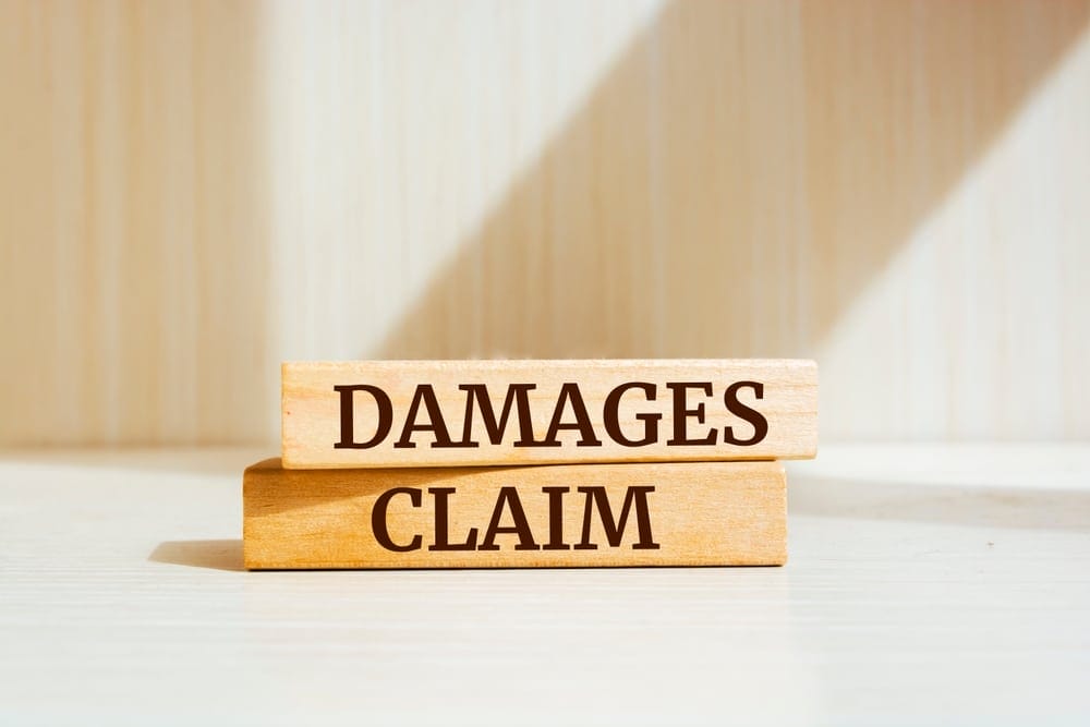 Wooden blocks displaying the words "damages claim" on a table.